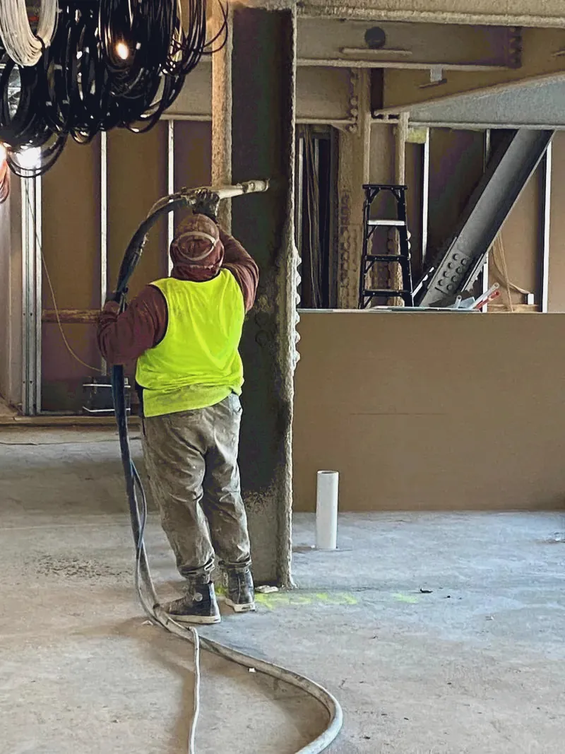 Cementitious spray application to a column during interior fitout