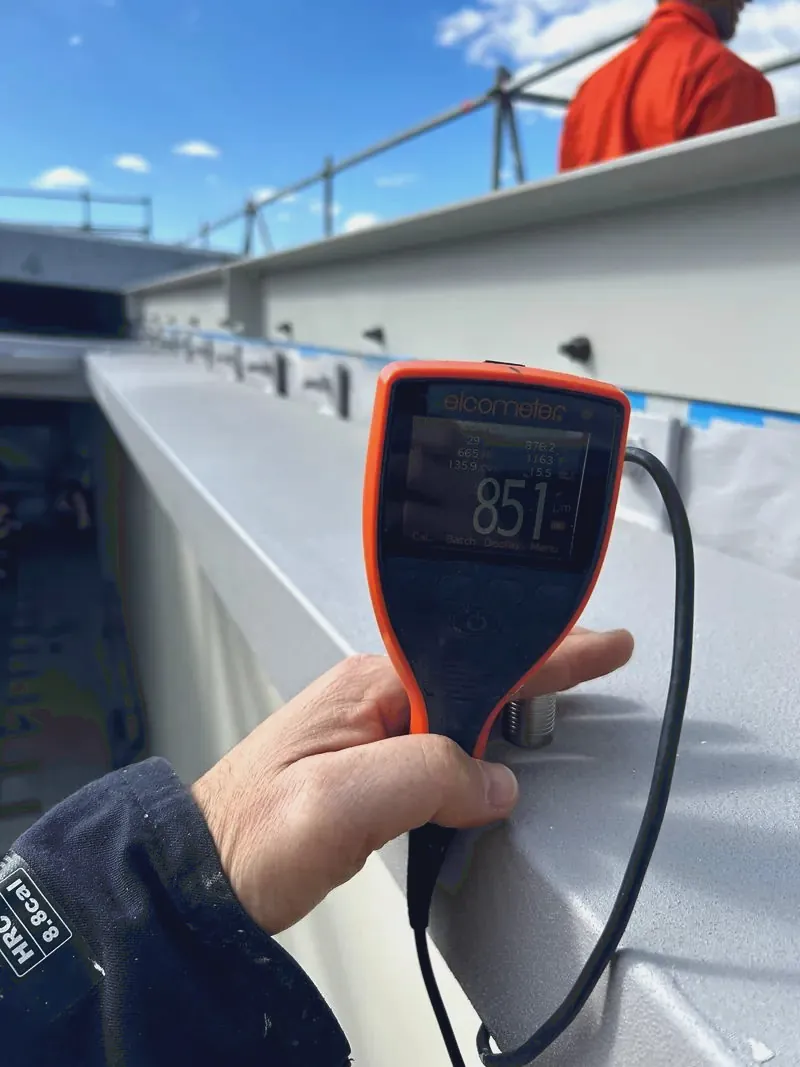Dry film thickness gauge reading 851 microns against coated structural steel on site